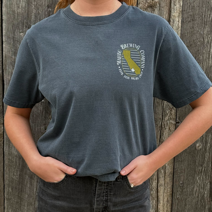 Person wearing a dark blue t-shirt with a logo against a wooden background